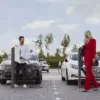 Zwei Alfen Eve Double auf Standfüßen auf einem Parkplatz, zwei Personen laden ihre Autos (Wallboxen nicht im Lieferumfang)