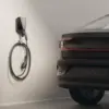 Easee Charge Pro M&E an der Wand mit Easee-Ladekabel am Haken neben einem Elektroauto