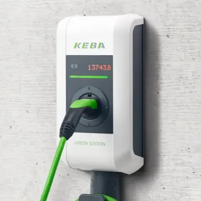 Nahansicht Keba KeContact P30 x-series: KEBA-Logo, rote Zähleranzeige und grüne LED-Leiste im dunklen Bedienfeld, darunter der eingesteckte Typ-2-Stecker in der Parkposition und der Schriftzug GREEN EDITION